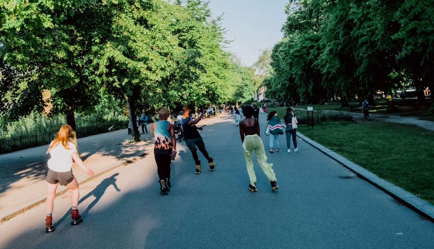 Várias pessoas andando de patins em uma via dentro de um parque