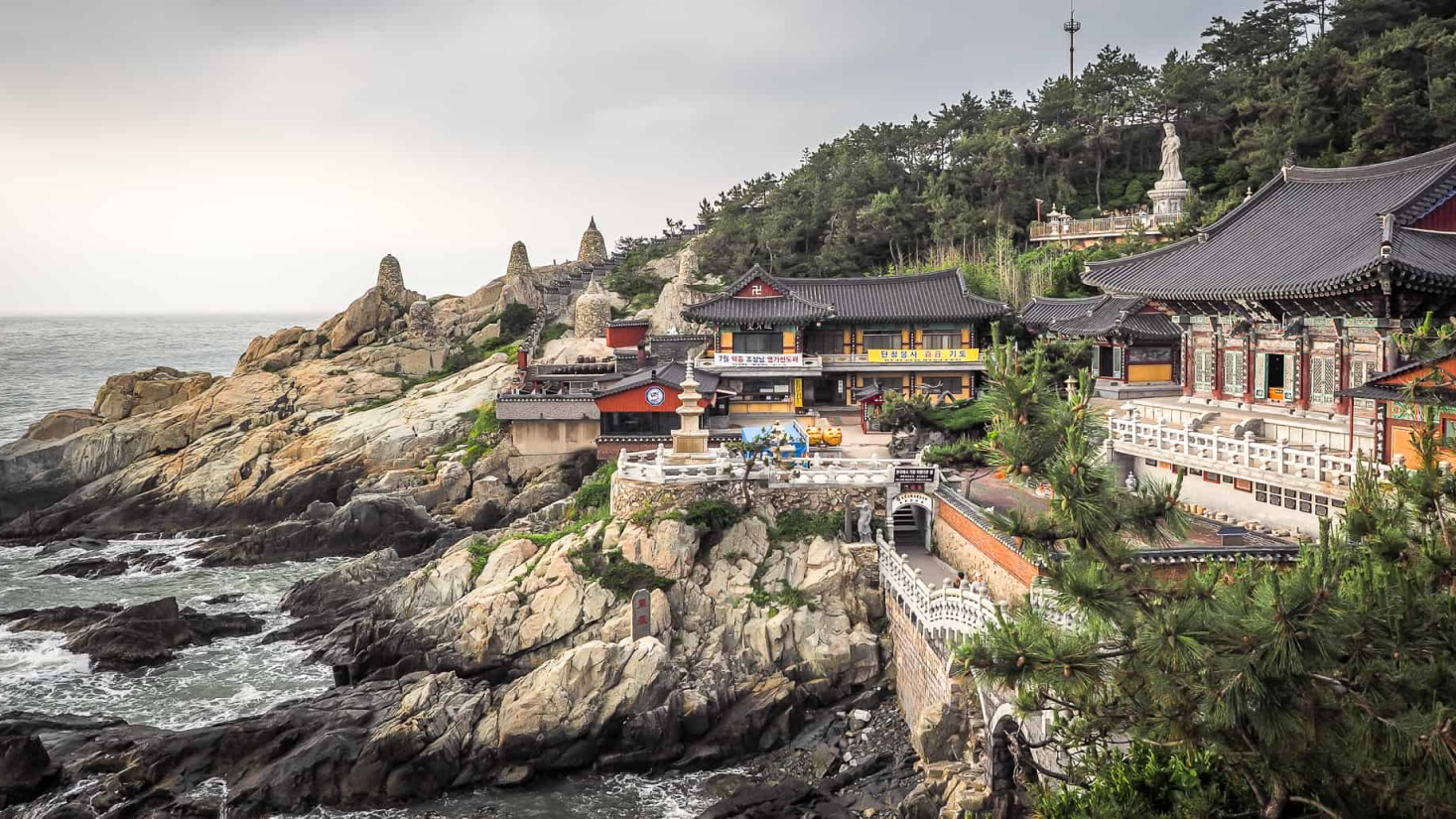 Região pedregosa e litorânea, mostra construções com arquitetura oriental, o mar e muitas árvores, representa muito bem a natureza e envolve as construções.